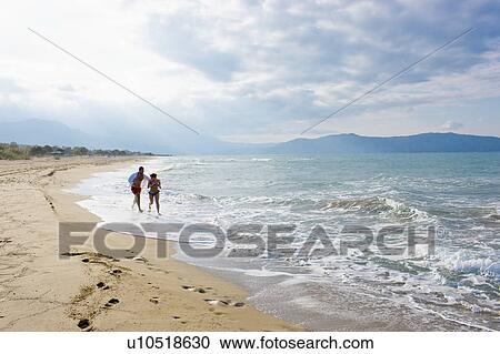 Stock Image - couple running on the beach. Fotosearch