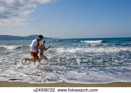Stock Image - couple running on the beach. Fotosearch