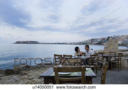 Stock Image - Couple sitting at waterfront cafe. Fotosearch