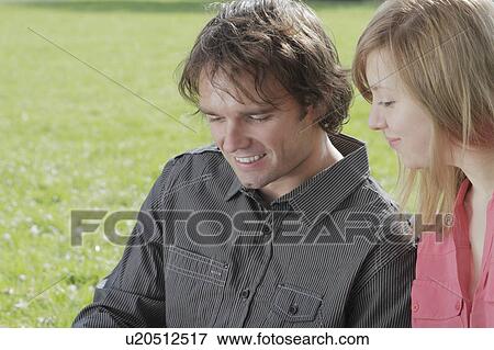 Couple sitting in park together View Large Photo Image Stock Photo - Couple sitting in park together. Fotosearch