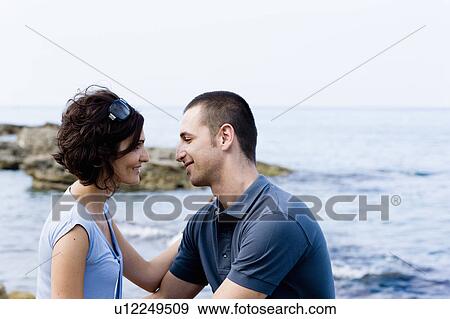 Stock Photo - Couple sitting together on waterfront. Fotosearch
