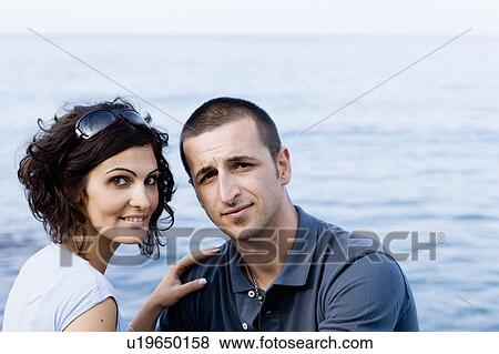 Couple sitting together on waterfront View Large Photo Image Stock Photo - Couple sitting together on waterfront. Fotosearch