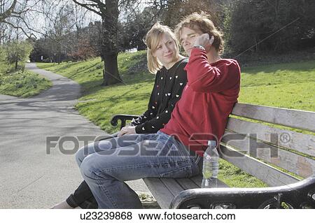 Couple talking on cell phone in park View Large Photo Image Stock Photo - Couple talking on cell phone in park. Fotosearch