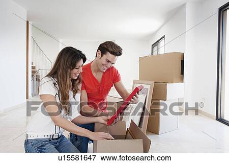 Couple unpacking box in new home View Large Photo Image Stock Photo - Couple unpacking box in new home. Fotosearch