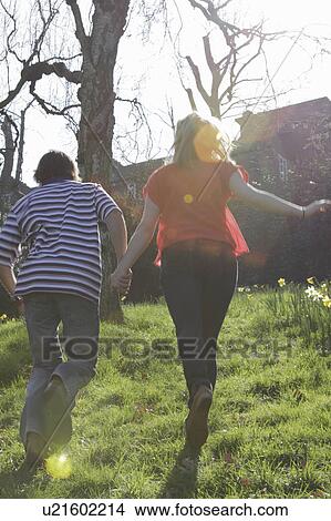 Picture - Couple walking hand-in-hand in park. Fotosearch