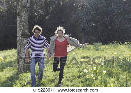 Couple walking hand-in-hand in park View Large Photo Image Stock Image - Couple walking hand-in-hand in park. Fotosearch