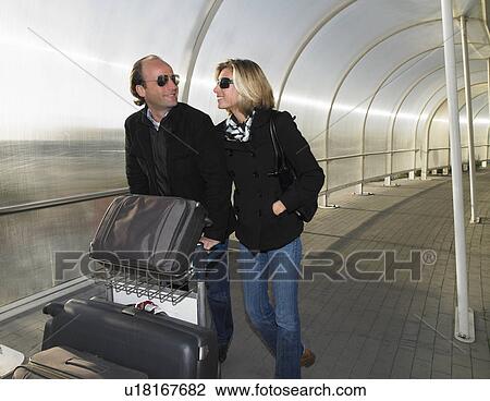 Stock Image - Couple with luggages on a trolley. Fotosearch