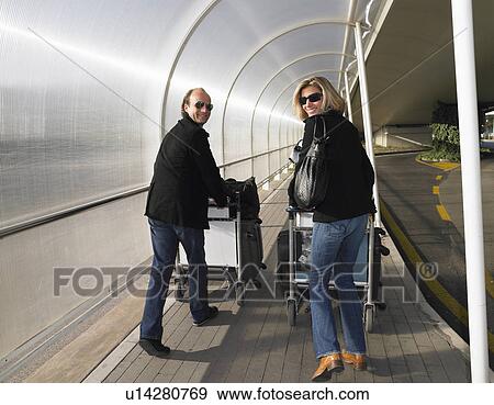 Stock Photo - Couple with luggages on a trolley. Fotosearch