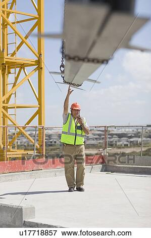 Stock Photo - Crane and older worker doing his job. Fotosearch