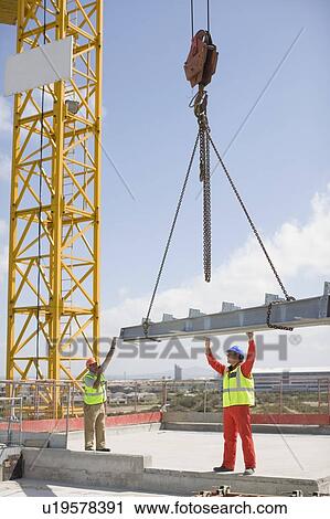 Stock Image - Crane and workers on construction site. Fotosearch
