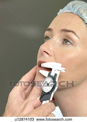 Stock Image - Doctor preparing patient for surgery. Fotosearch