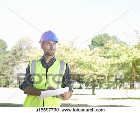 Stock Image - Engineer in fields, taking notes. Fotosearch