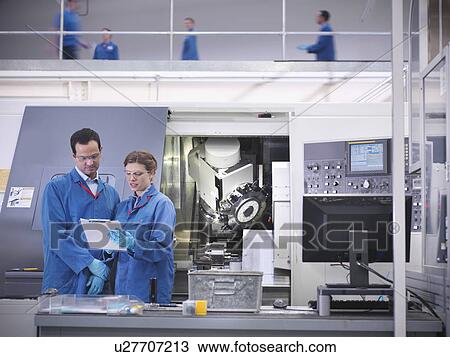 Stock Image - Engineers with machinery in factory. Fotosearch