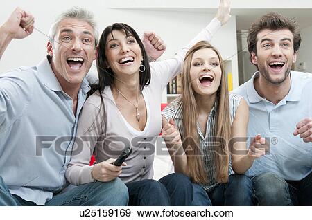 Stock Photo - Excited friends watching sport on TV. Fotosearch