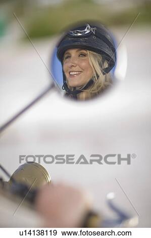 Face of a woman with helmet in rear mirror View Large Photo Image Stock Photo - Face of a woman with helmet in rear mirror. Fotosearch