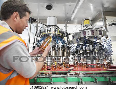 Factory worker examining bottle in plant View Large Photo Image Picture - Factory worker examining bottle in plant. Fotosearch