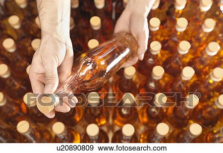 Stock Photo - Factory worker examining bottle in plant. Fotosearch