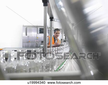 Stock Image - Factory worker examining bottles. Fotosearch