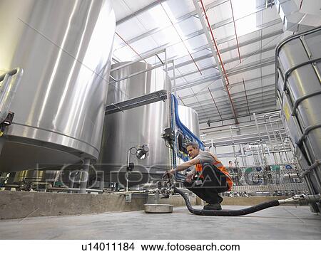 Picture - Factory worker examining storage tanks . Fotosearch