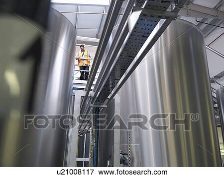 Factory worker examining storage tanks View Large Photo Image Stock Photo - Factory worker examining storage tanks . Fotosearch
