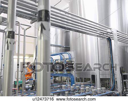Stock Photograph - Factory worker examining storage tanks. Fotosearch