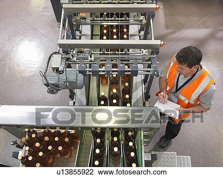 Stock Image - Factory worker in bottling plant. Fotosearch