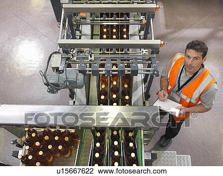 Stock Image - Factory worker in bottling plant. Fotosearch