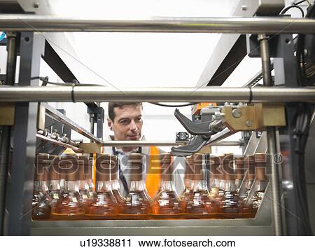 Stock Image - Factory worker in bottling plant. Fotosearch