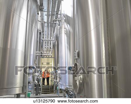 Factory workers examining storage tanks View Large Photo Image Stock Image - Factory workers examining storage tanks. Fotosearch