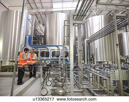 Factory workers examining storage tanks View Large Photo Image Stock Photo - Factory workers examining storage tanks . Fotosearch