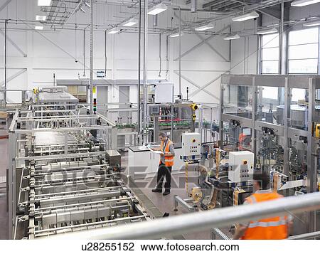 Stock Image - Factory workers in bottling plant. Fotosearch