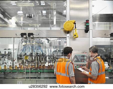 Stock Image - Factory workers in bottling plant. Fotosearch