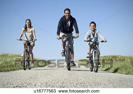 Stock Image - Family cycling down country road. Fotosearch