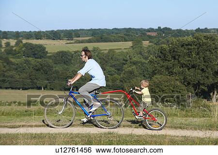 Father and son on bicycle in the fields View Large Photo Image Stock Photograph - Father and son on bicycle in the fields. Fotosearch