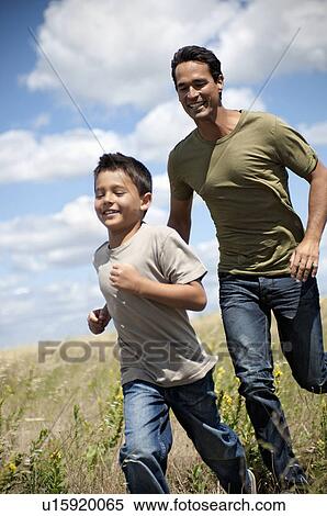 Stock Photography - Father and son running through a field. Fotosearch