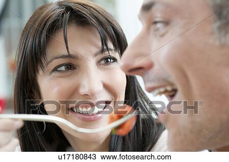 Stock Image - Feeding with tomato at lunch. Fotosearch