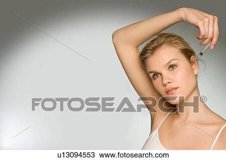 Stock Image - Female with syringe gazing into distance. Fotosearch