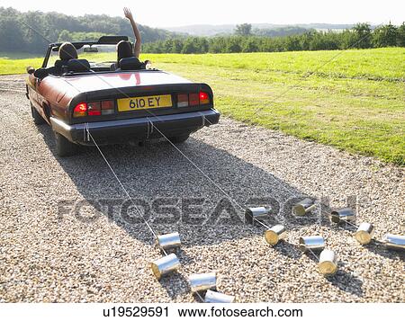 Stock Image - Freshly married couple in car, goodbye. Fotosearch