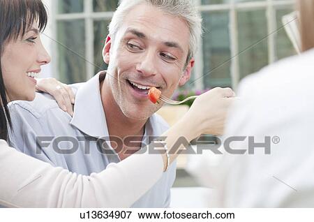 Stock Photo - Friends feeding together at lunch. Fotosearch