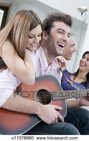 Stock Image - Friends playing guitar and having fun. Fotosearch