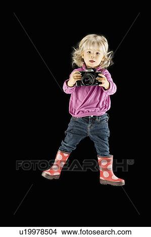Picture - Girl and camera against black background. Fotosearch