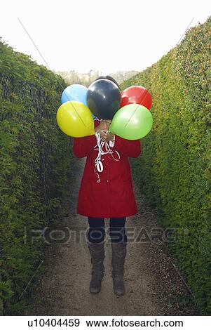 Girl holding balloons in front of face View Large Photo Image Stock Photo - Girl holding balloons in front of face. Fotosearch