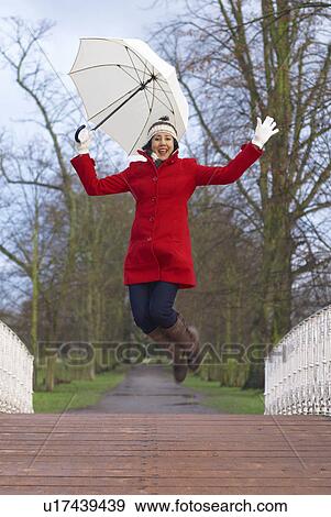 Stock Photo - Girl in red jacket with brolley in park. Fotosearch