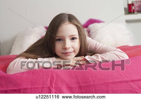 Stock Photograph - girl lying on back looking at phone. Fotosearch