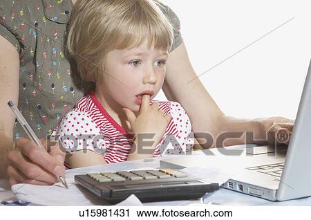 Stock Image - girl on mothers lap looking at computer. Fotosearch