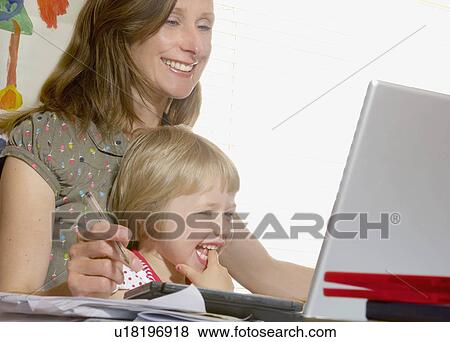 girl on mothers lap looking at computer View Large Photo Image Stock Photo - girl on mothers lap looking at computer. Fotosearch