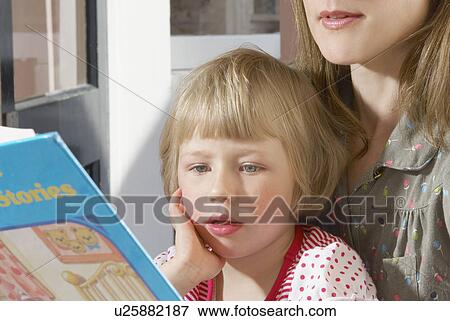 girl on mothers lap reading book View Large Photo Image Stock Photo - girl on mothers lap reading book. Fotosearch