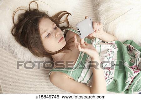 Stock Photograph - girl playing game on a phone. Fotosearch