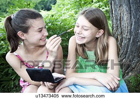 Stock Photography - Girl putting make-up on sister. Fotosearch