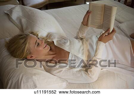 Stock Image - Girl reading in bed. Fotosearch